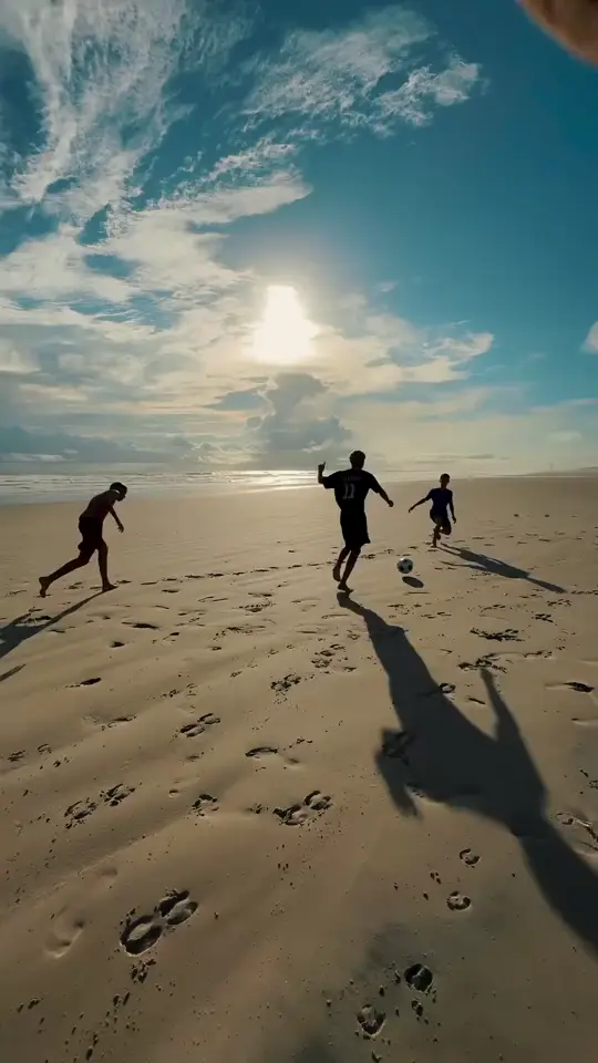 Crianças correndo na areia da Praia do Barro Vermelho ao entardecer